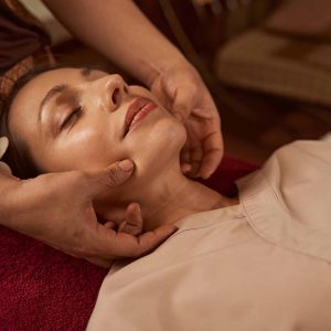 Serene young woman receiving Thai face massage