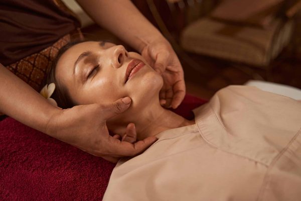 Serene young woman receiving Thai face massage